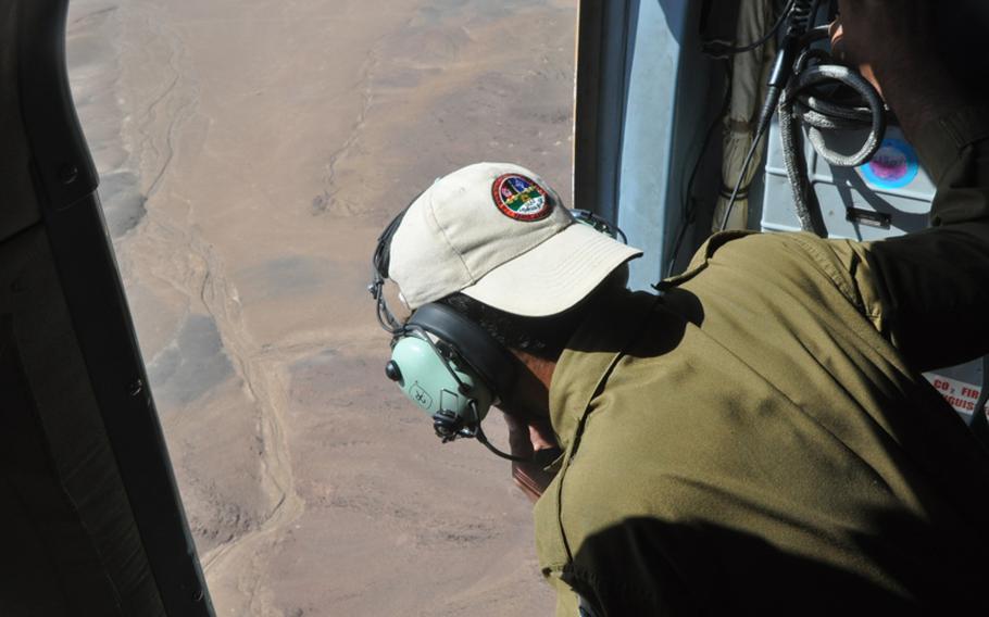 Mohammad Haroon, training to become a helicopter crew chief with the Afghan Air Force, peers out of a Russian-made Mi17 helicopter during a training flight near Shindand Air Base in Herat province.