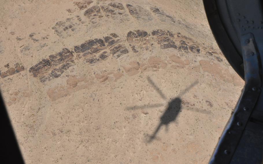 The shadow cast by a Russian-made Mi-17 helicopter, used to train Afghan Air Force pilots, is shown from the open loading door of the aircraft during a training flight over mountains near Shindand Air Base in Herat province.