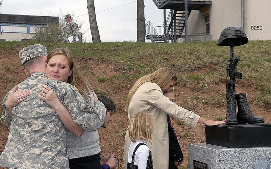 Carla Gilstrap, 37, hugs Army Sgt. Matthew Glick on Wednesday next to a memorial dedicated to her brother, Staff Sgt. Edward Dixon, and the eight other soldiers from the 170th Infantry Brigade Combat Team killed during the unit's last deployment to Afghanistan. Dixon's wife, Jana, and children, Brianna, 7, and Oliver, 8, stand next to the memorial. Dixon was one of four soldiers from the brigade killed when their vehicle overturned in Afghanistan. Glick, who knew all of them, said ''they were my true brothers.''