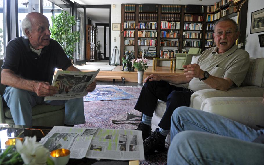 Ulrich Durst, left, and Eberhard Knobloch discuss the Panzer firing range May 10 at Durst's home in the Rauher Kapf neighborhood of Boeblingen, Germany, while looking at newspaper articles on Panzer Kaserne and the range. Rauher Kapf sits about 300 yards from the range and both men are residents of the neighborhood.