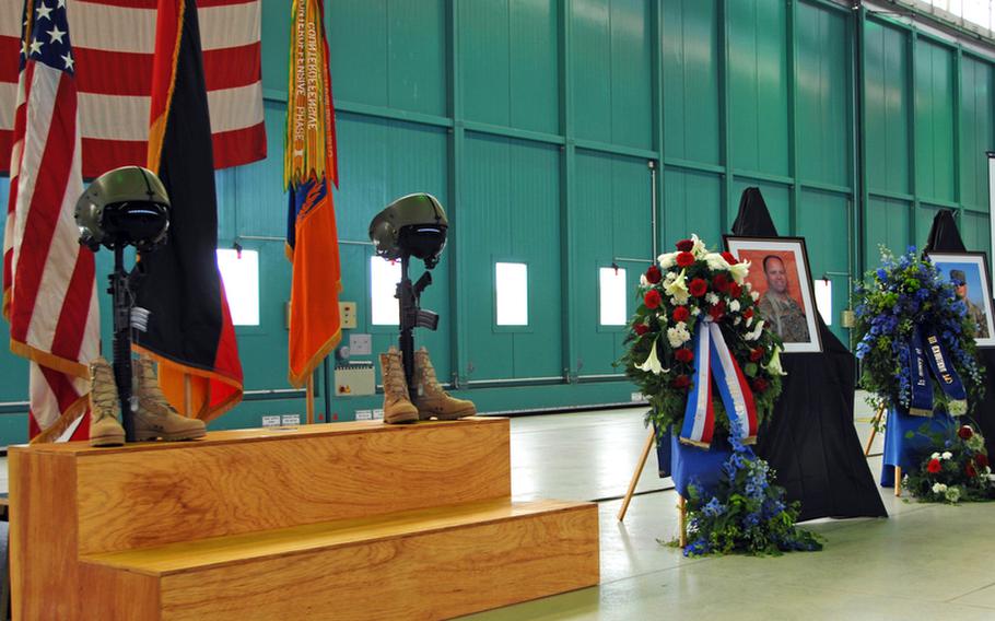 A display of aviation helmets, weapons and boots, along with photos of Chief Warrant Officer 5 John C. Pratt and Capt. John "Jay" Brainard honor the two soldiers at a memorial service Tuesday in Ansbach, Germany. Pratt and Brainard, of the 12th Combat Aviation Brigade, were killed in a helicopter crash in Afghanistan on May 28.