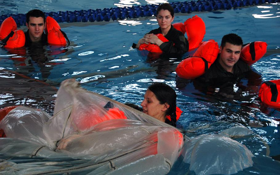 Capt. Carmen Young, foreground, of Xenia, Ohio,  and other members of the 374th Airlift Wing, practice freeing themselves from a parachute canopy during water survival training at Yokota Air Base, Japan, in April.