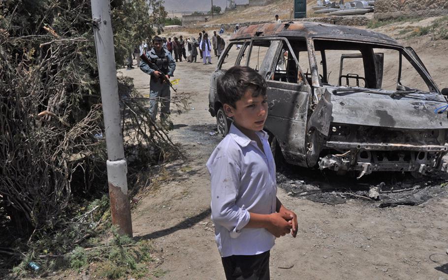 A boy identified as a hostage by Afghan security officials stands outside a lakeside resort on the outskirts of Kabul that was the scene of a 12-hour insurgent attack that left 18 people dead.