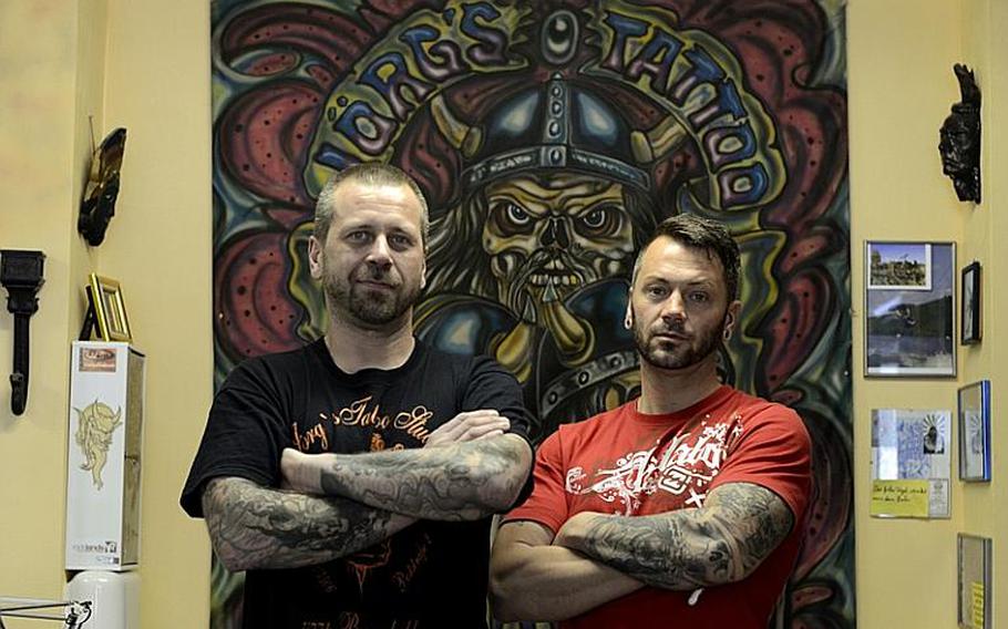 Jörg Aldensell, left, and Oliver Riede, of Jörg&#39;s Tattoo & Piercing Studio in Baumholder, Germany, aren&#39;t concerned that the 170th Infantry Brigade Combat Team is leaving later this year. Riede said their business has a good reputaton.