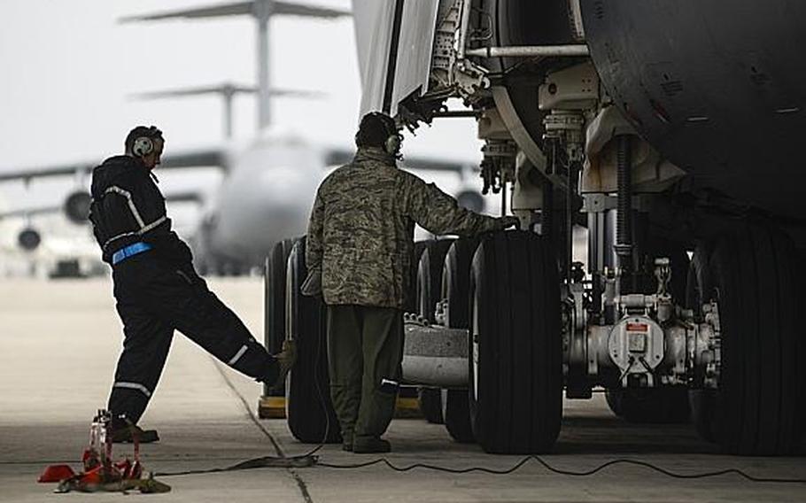 Air Force Staff Sgt. Brian Parker, left, a crew chief with the 721st Air Mobility Group, and Tech. Sgt. Greg LeVengie, a loadmaster with the 337th Airlift Squadron, inspect a C-5 Galaxy at Ramstein Air Base, Germany, on Tuesday, Jan. 8, 2013.