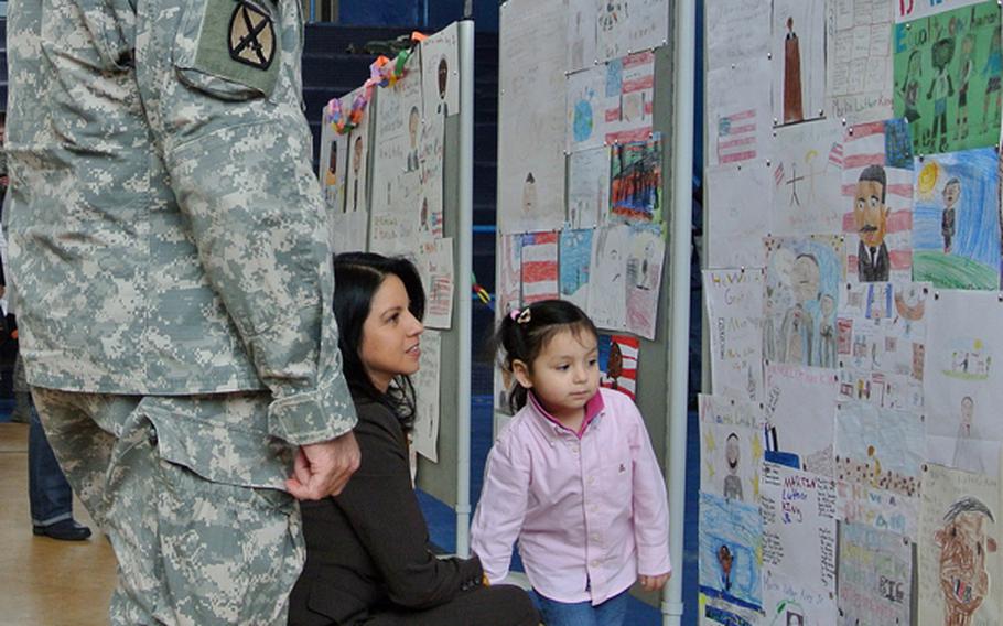 At the Martin Luther King Jr. Day celebration, U.S. Army Garrison Wiesbaden commander Col. David Carstens, along with Cynthia Alvarado with her daughter Maddison, look at posters  about King made by Hainerberg Elementart School students.
