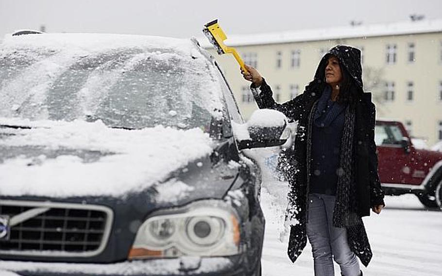 Damaris Hay removes snow from her vehicle on Kleber Kaserne, Germany, before going home Tuesday afternoon. Kaiserslautern Military Community members were released from work early due to inclement weather. Civilian employees in Wiesbaden, Bamberg and Schweinfurt also were released early.