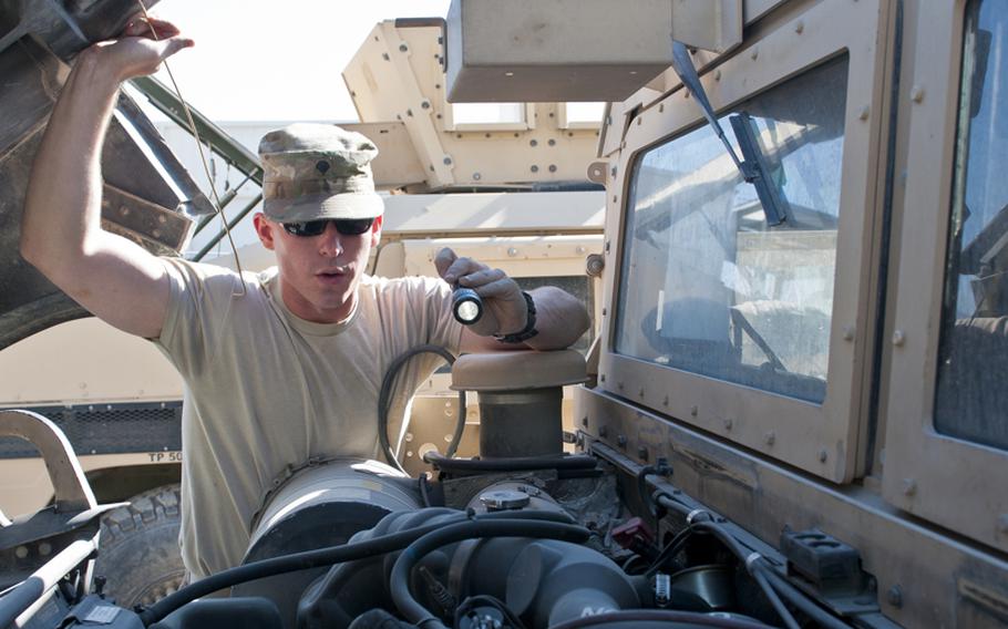 Spc. Patrick Claybaugh, a member of the 316th Sustainment Command (Expeditionary), checks the engine bay of a Humvee for anything that may prevent it from passing customs while enroute to the United States. 