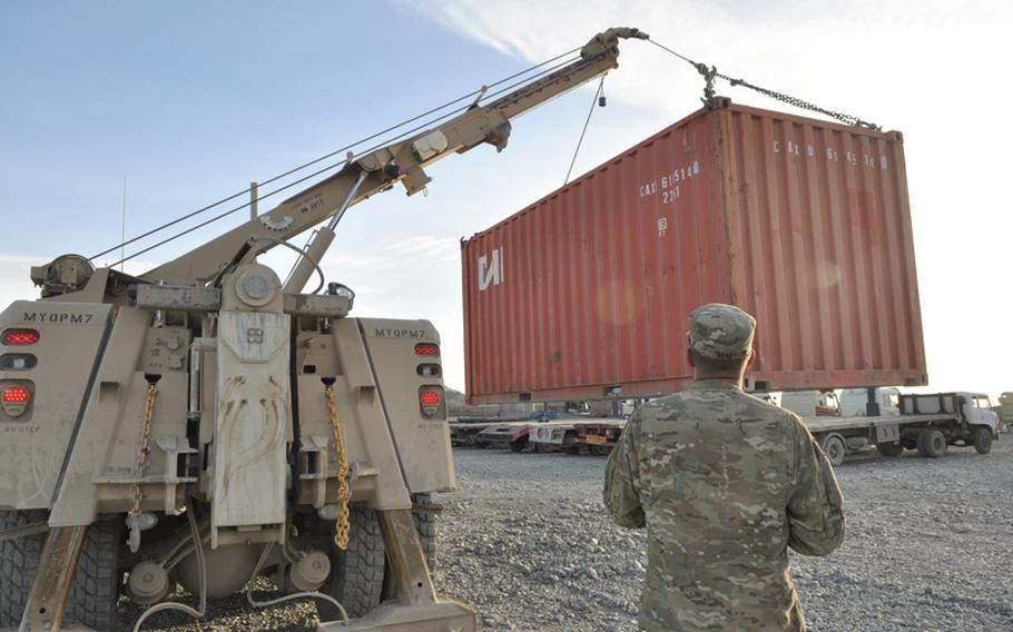 A soldier from Combined Task Force Raider watches as a container is loaded onto the back of an Afghan tractor trailer. The trucks are then driven to a larger Forward Operating Base in the region, where the U.S. troops will eventually relocate.