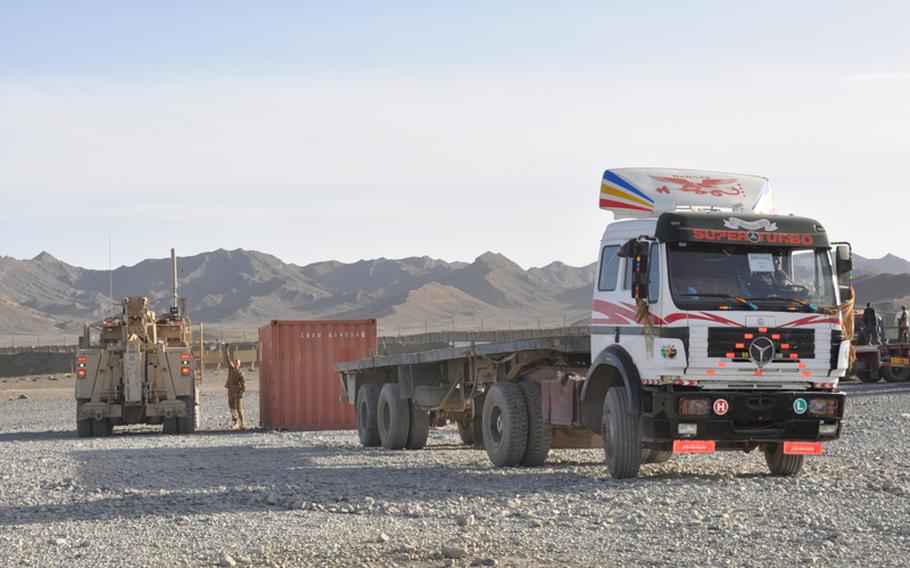 A soldier from Combined Task Force Raider directs a local Afghan truck driver to back up and load a container onto the flat bed. 