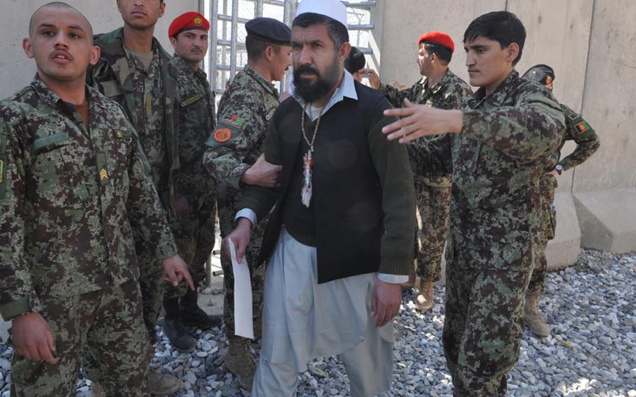 A prisoner is led away after being released Monday as part of a ceremony to mark the handover of Parwan Prison from U.S. to Afghan control. Delays in the handover have raised tensions between Washington and Kabul.