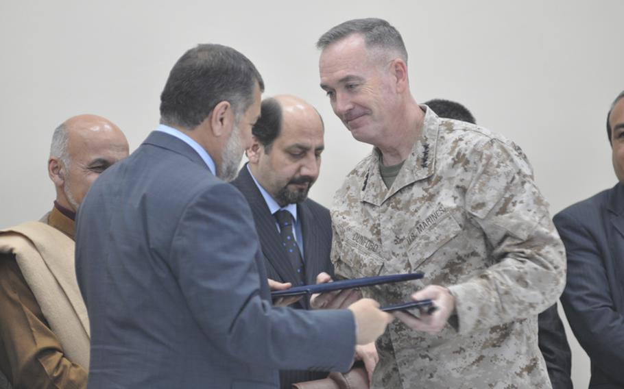 Top coalition commander Gen. Joseph Dunford, right, and Afghan Minister of Defense Bismillah Khan Mohammadi finalize an agreement to handover Parwan Prison at Bagram Airfield on Monday. Human rights groups have criticized Afghan prisons for being rife with torture and many worry conditions could worsen at Parwan Prison under Afghan control.