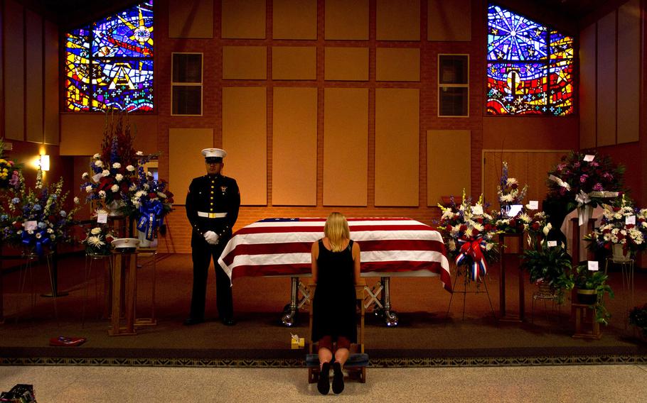 Lance Cpl. Isaac Ramirez, Marine Wing Support Squadron 471, stands guard over Pfc. Nicolai 'Cola' Jensen at the Church of St. Patrick June 24 while Jensen's girlfriend, Abby Cuttell, says goodbye. Jensen died while attending infantry school.