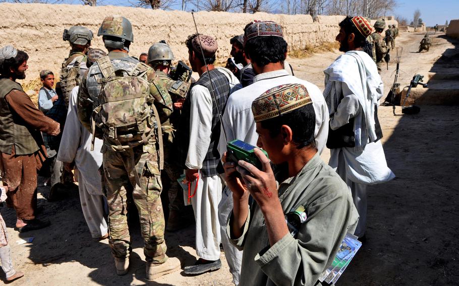 U.S. Psychological Operations soldiers hand out radios to children in a village in southern Afghanistan. The new radio shows on Army-run stations are seeking to reach wider audiences.
