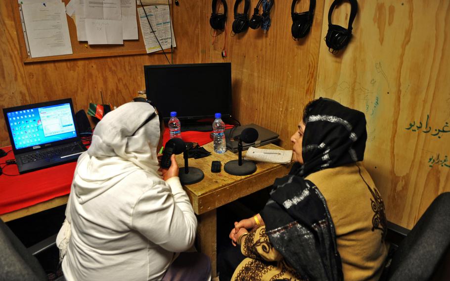 Zubiah Fedaie, left, a linguist for American civil affairs at Forward Operating Base Spin Boldak, takes a call on a cellphone during a call-in radio show featuring Afghan Uniform Police Capt. Noorul Hayat. The weekly show, called ''Light of the House'' is aimed at local women and families and issues of particular interest to them.