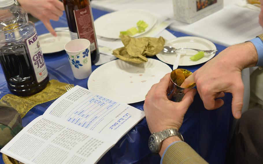 Participants in Monday's Passover seder at U.S. Army Garrison Grafenwohr transfer drops of wine from their cups onto their plates to represent the 10 plagues in Egypt during Jewish captivity. Some 50 people attended the first of four Seders held by U.S. Army Europe's only Jewish chaplain, Capt. Andrew Shulman.
