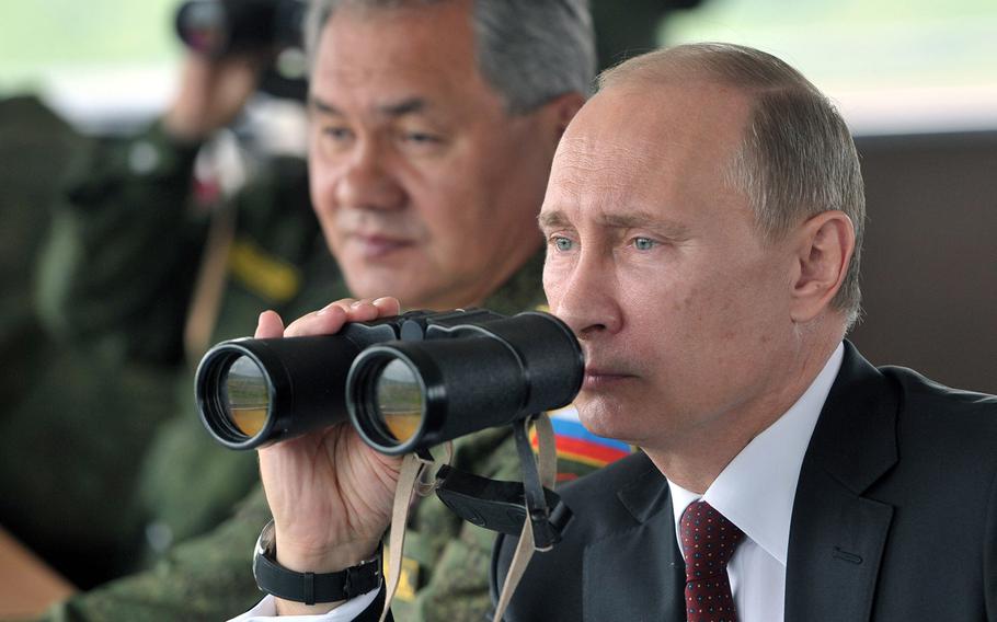 In this file photo from Tuesday, July 16, 2013, Russian President Vladimir Putin watches military exercises near Yuzhno-Sakhalinsk on Sakhalin Island. The maneuvers in Siberia and the island in the north Pacific Ocean involved 160,000 troops and about 5,000 tanks -- a massive show of force unprecedented since the Soviet times. Defense Minister Sergei Shoigu sits at left. 