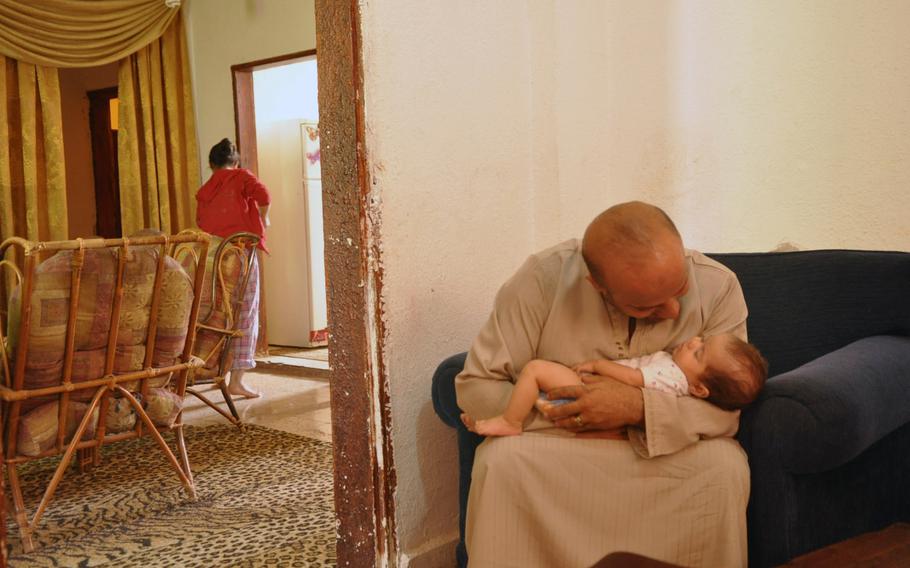 Muhammad Halaweh embraces his niece in the home that he shares with his sister and brother-in-law. His sister cleans in the small apartment that they've been renting inside the Baqa'a refugee camp in Jordan. Within the past year, Baqa'a has lost its title as Jordan's largest refugee camp to the Zataari Syrian refugee camp in northern Jordan, which houses around 130,000 Syrian refugees.