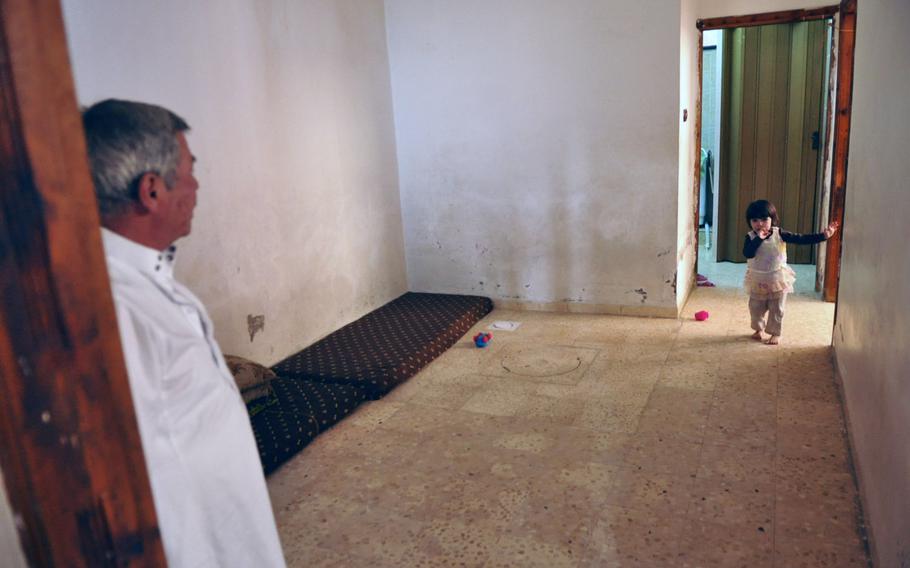 Ibrahim Abu Dayes wathces as his granddaughter walks through their empty home in the Baqa'a refugee camp near Amman, Jordan. Dayes is a Syrian refugee who moved into the camp 1/1 2 years ago because of the Syrian civil war. He says the Palestinians have been extraordinarily accommodating to him and his family since they arrived.