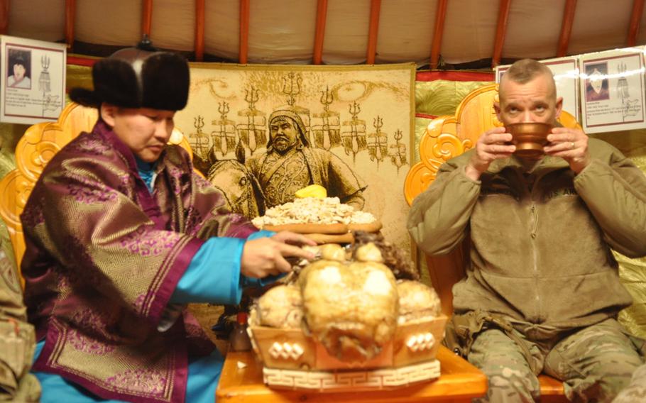 U.S. Army Col. Wallace Steinbrecher, garrison commander for Camp Marmal Regional Command North, sits with a Mongolian soldier in his traditional wardrobe as he serves his coalition counterparts traditional Mongolian tea and a lamb dish prepared to bring in the new year.