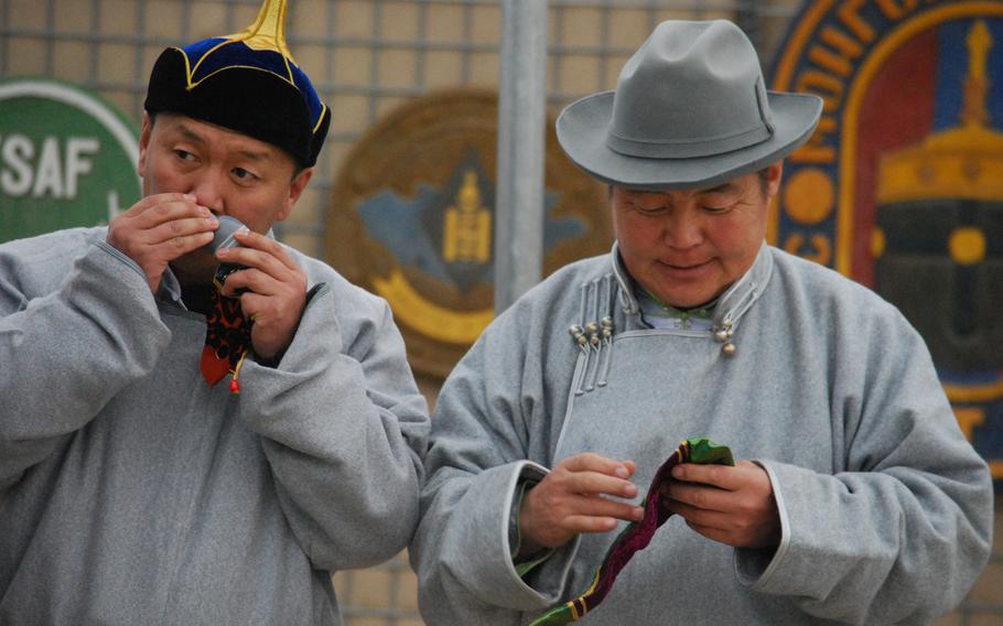 Two Mongolian soldiers dressed in traditional Mongolian garb smell an incense that was prepared for the Lunar New Year celebration at Camp Marmal in Mazar-i-Sharif, Afghanistan, Jan. 31, 2014.
 
