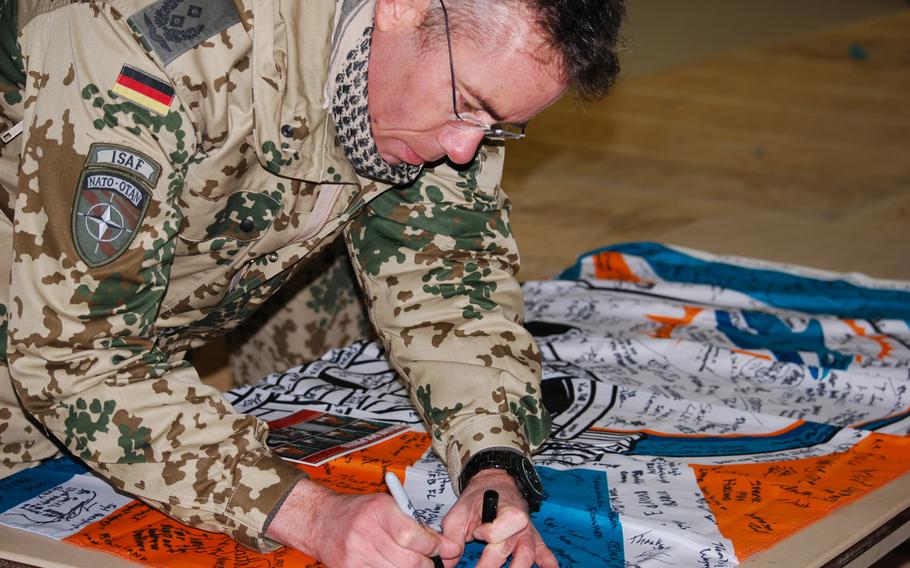 A German coalition servicemember signs a Miami Dolphins banner at Camp Marmal in Mazar-e-Sharif, Afghanistan on Sunday, Feb. 2, 2014. The banner, which was signed by most of the soldiers who attended a meet and greet session with a group of Miami Dolphins cheerleaders and two former players, is set to be hung at the Dolphins' football stadium in Miami.