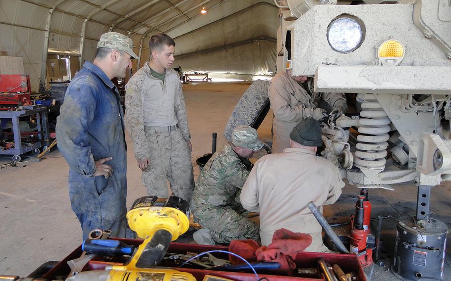 From left, Merab Beridze, Cpl. Parker Fletcher, Temur Okruashvili (squatting), Gela Sadgobelashvili (squatting) and Gocha Ushveridze (standing) work together to repair an MRAP in the Georgian vehicle maintenance shop at Camp Leatherneck, Afghanistan. Fletcher is part of the Georgian Liaison Team, a small group of Marines that advises and assists Georgian troops here.