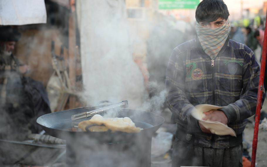 7:00 a.m. A man prepares dough for paratha, a fried bread often eaten for breakfast in Kabul, outside the city's main wholesale produce market. 
