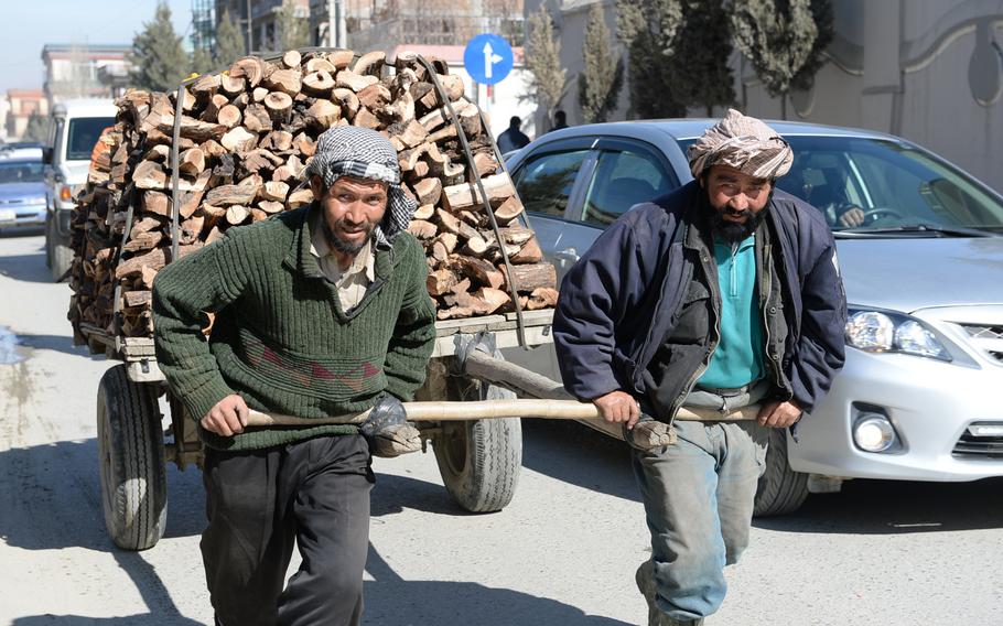 10:30 a.m. Men push a firewood cart down a busy road in the Sher Pur neighborhood of Kabul. Despite the glut of cars in the city, much of the goods in Kabul are transported by foot power or on carts drawn by horses and donkeys. 