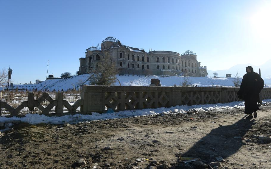 4:02 p.m. A woman walks past Darulaman Palace, a former residence of the king of Afghanistan in western Kabul that was destroyed during Afghanistan's civil war in the early 1990s. 