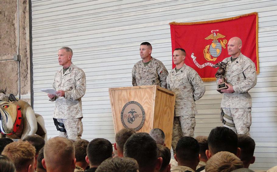 Marine Commandant Gen. James Amos, left, reads the Ground Logistics Unit of the Year award citation for R4OG, while the unit's commander, Lt. Col. John Flynn, and its top enlisted Marine, 1st Sgt. David White, stand ready to receive the award from the sergeant major of the Marine Corps, Sgt. Maj. Micheal Barrett.