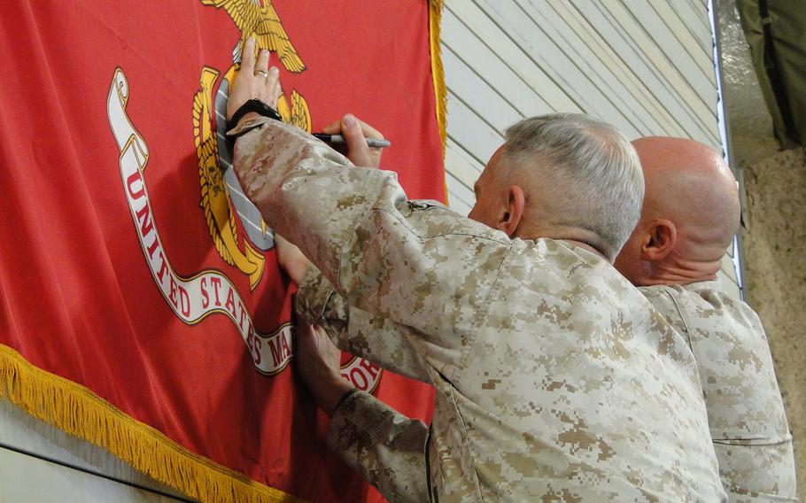Marine Commandant Gen. James Amos and Sgt. Maj. of the Marine Corps Micheal Barrett sign R4OG's flag on Tuesday.