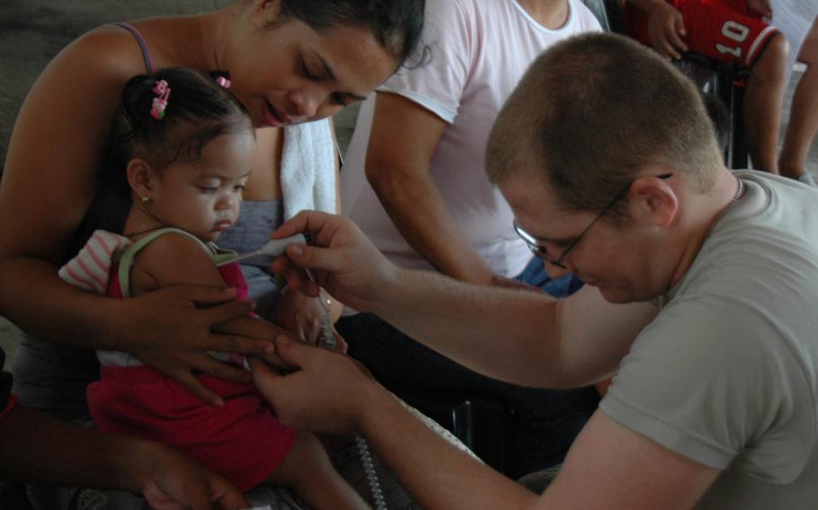 U.S. Army Spc. Phillip DeVictor, 22, takes a child's temperature during health checks provided by U.S., Japanese and Australian personnel in Tacloban City, the Philippines, in July 2014.