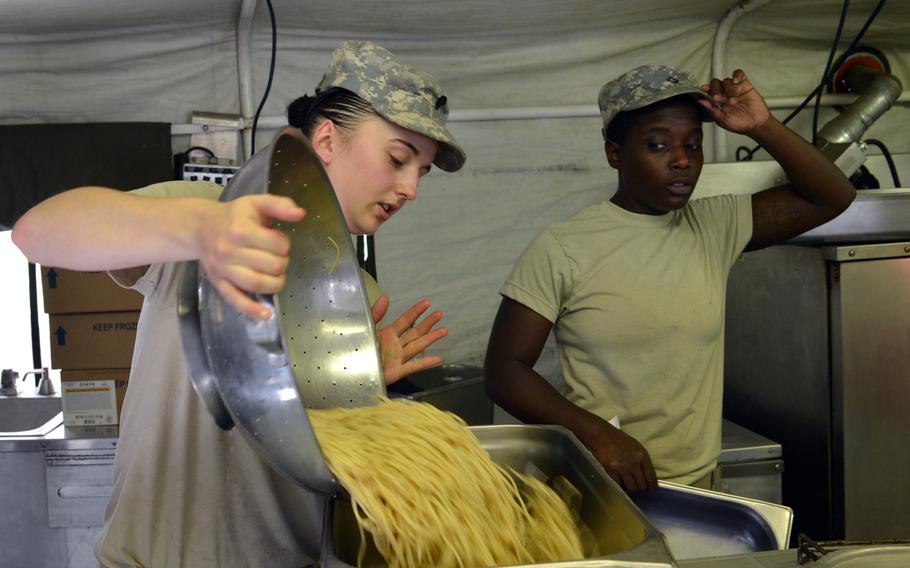 Pfc. Taija Stewart watches Spc. Katherine Dillon pour a colander of noodles into a pan as they prepare dinner for their fellow 5th Battalion, 7th Air Defense Artillery Regiment soldiers at a Turkish army base in Gaziantep, Turkey.