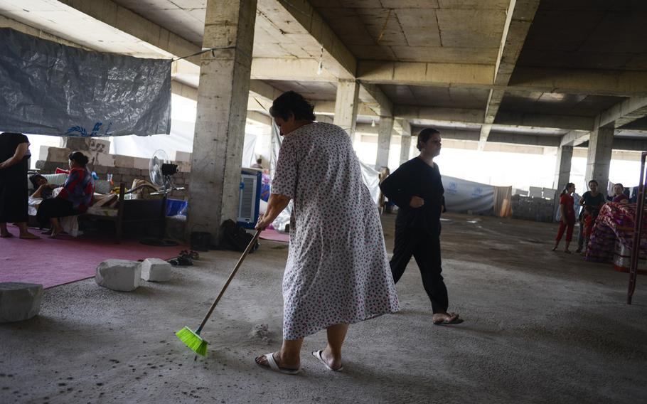 A displaced Iraqi sweeps her living area in an unfinished commercial building in Irbil, Iraq, Aug. 21, 2014. The Christians fled their homes in fear of the Islamic State's advance in the Mosul region.