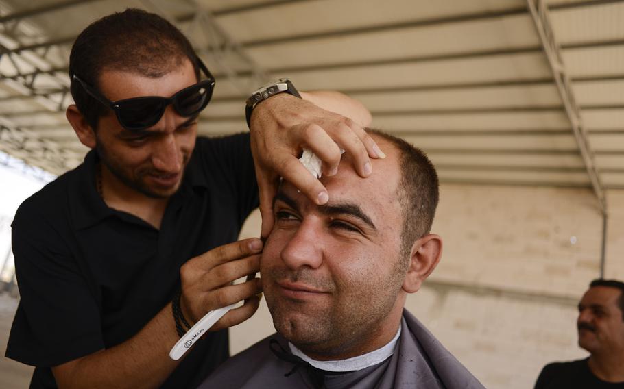 An Iraqi barber gives haircuts in the unfinished commercial building in Irbil, Iraq, Aug. 21, 2014. The Christians fled their homes in fear of the Islamic State's advance in the Mosul region.