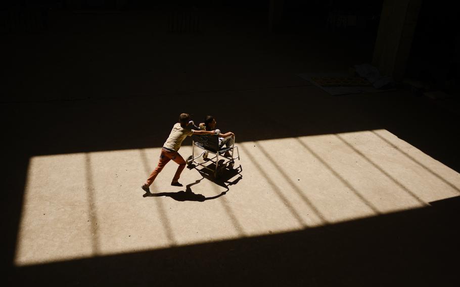 Displaced Iraqi children play with an old wheelchair inside their camp, an unfinished commercial building in Irbil, Iraq, Aug. 21, 2014. The Christians fled their homes in fear of the Islamic State's advance in the Mosul region.