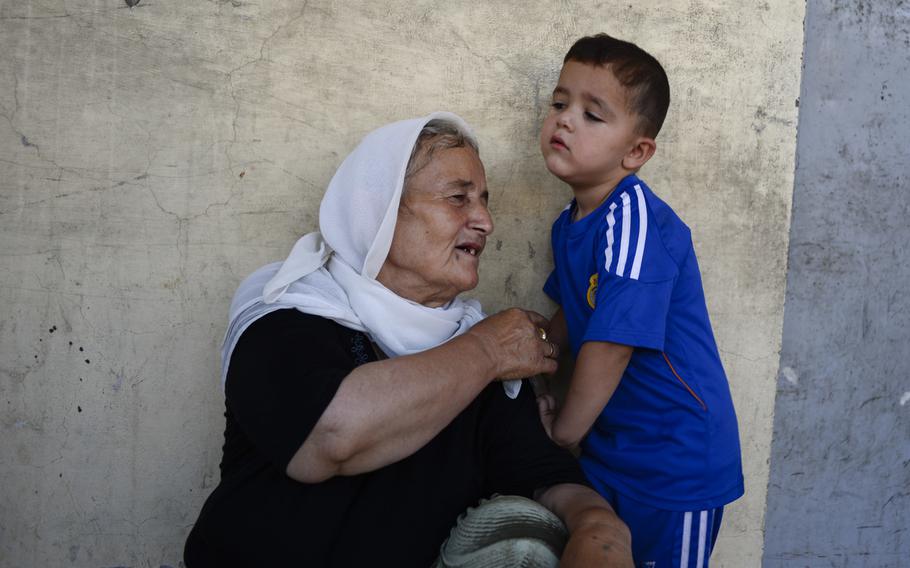 A displaced elderly Yazidi woman interacts with a boy in the school where they've been given shelter in the Ankawa district of Irbil, Iraq, Aug. 24, 2014. Fear of advances by the Islamic State drove them from their homes.