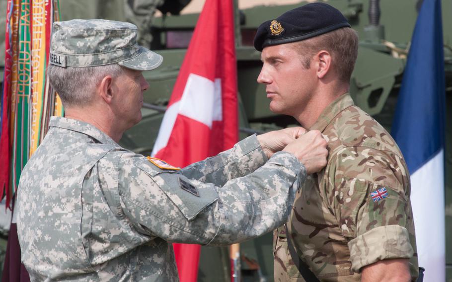 U.S. Army Europe commander, Lt. Gen. Donald Campbell, pins the Expert Field Medical Badge on British Capt. Michael Court during a ceremony held in Grafenwoehr, Germany, Sept. 9, 2014. Court was one of 12 international soldiers to be awarded the badge following five days of competition.