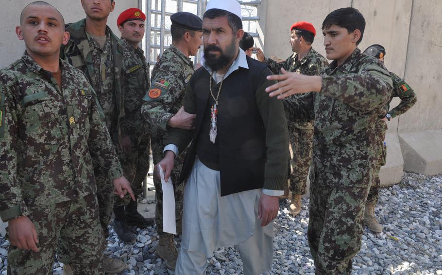 A prisoner is led away after being released on March 25, 2013, as part of a ceremony to mark the handover of Parwan Prison from U.S. to Afghan control. Delays in the handover raised tensions between Washington and Kabul.