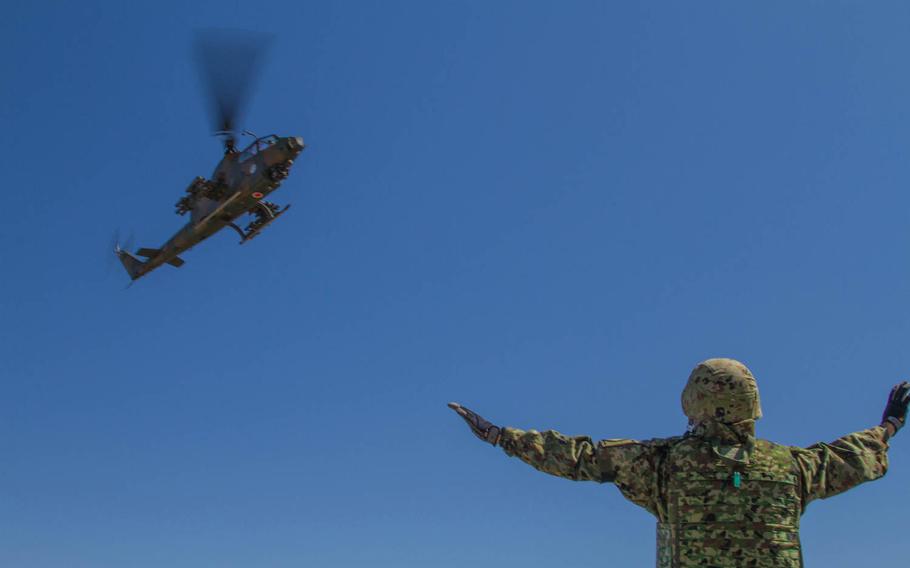 A Japan Ground Self-Defense Force member guides a Cobra anti-tank helicopter onto a forward aircraft refueling point at Yakima Training Center, Wash., Sept. 4, 2014. The exercise was part of Operation Rising Thunder, a combined operation between the Army and Japan designed to increase interoperability.