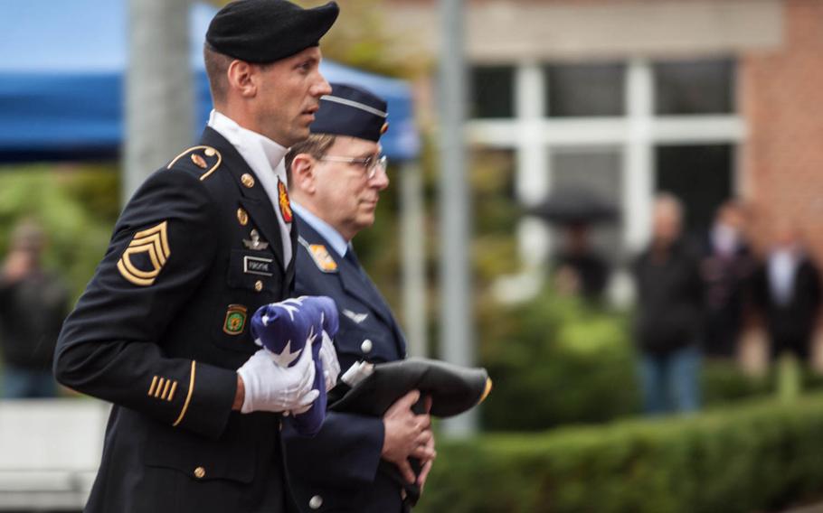 U.S. Army Sgt. 1st Class Robert Forsythe and a German soldier carry their countries' flags after the colors were lowered for the last time Friday, Sept. 12, 2014, at Warner Barracks in Bamberg, Germany.
