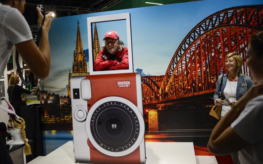 A visitor poses for a photo in one of the many portrait exhibitions that cleverly promote photography trade products on opening day of the Photokina trade fair, Tuesday Sept. 16, 2014, in Cologne, Germany.
