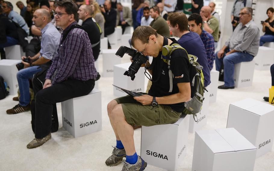 A Photokina visitor photographs a pamphlet during a presentation in the Sigma booth on opening day of the trade fair, Tuesday, Sept. 16, 2014, in Cologne, Germany.