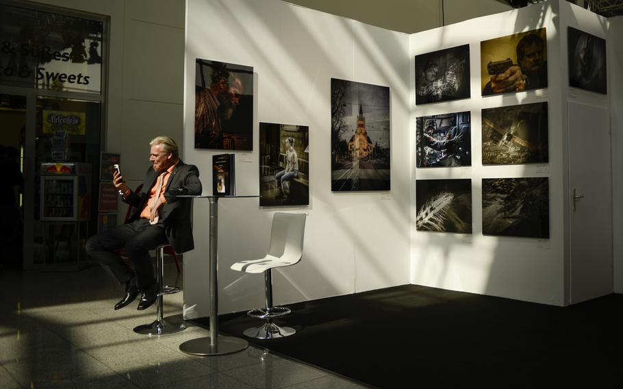 With an exhibit of photographs in the background, a man takes a break during opening day of Photokina, Tuesday Sept. 16, 2014, in Cologne, Germany.