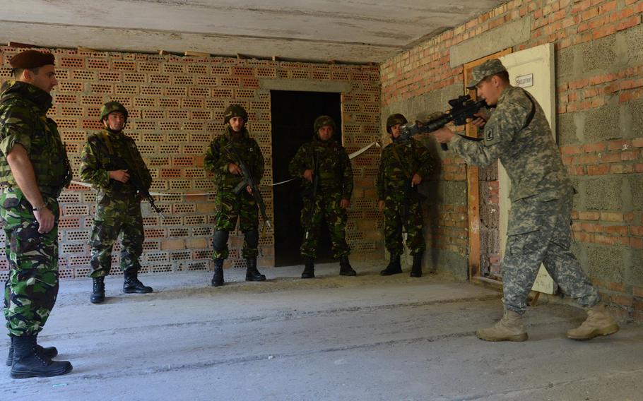 Staff Sgt. Julio Ortiz, right, of the 173rd Airborne Brigade, gives Romanian soldiers pointers on room-clearing during cordon-and-search training at Exercise Rapid Trident near Yavoriv, Ukraine, Thursday, Sept. 18, 2014.