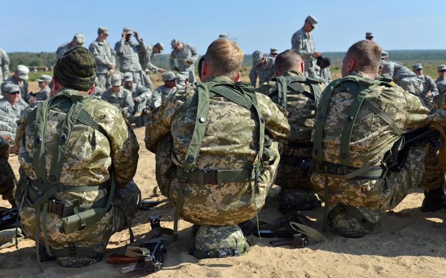 Ukrainian army cadets sit on their helmets during a break at Exercise Rapid Trident near Yavoriv, Ukraine, Wednesday, Sept. 17, 2014. In the background are soldiers from the U.S. Army's 173rd Airborne Brigade.