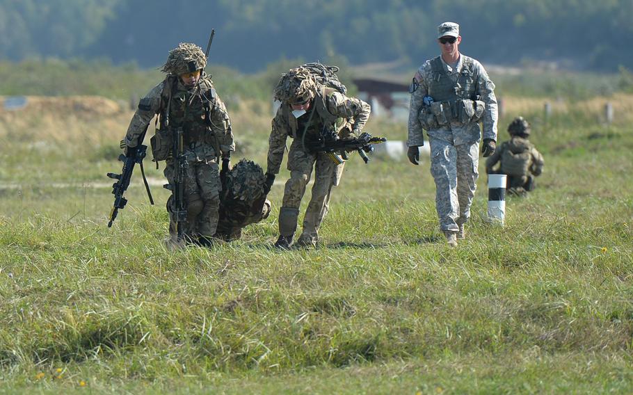 British soldiers carry a "wounded" comrade during training at Exercise Rapid Trident near Yavoriv, Ukraine, Thursday, Sept. 18, 2014, as Sgt. 1st Class Josh Ward of the Joint Multinational Readiness Center watches.