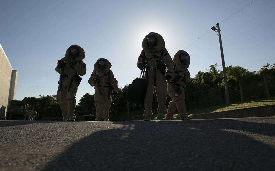 Chemical, biological, radiological and nuclear defense specialists search around a building for hazardous material during an assessment and consequence management response training event Aug. 27, 2014, at Marine Corps Air Station Futenma, Okinawa.