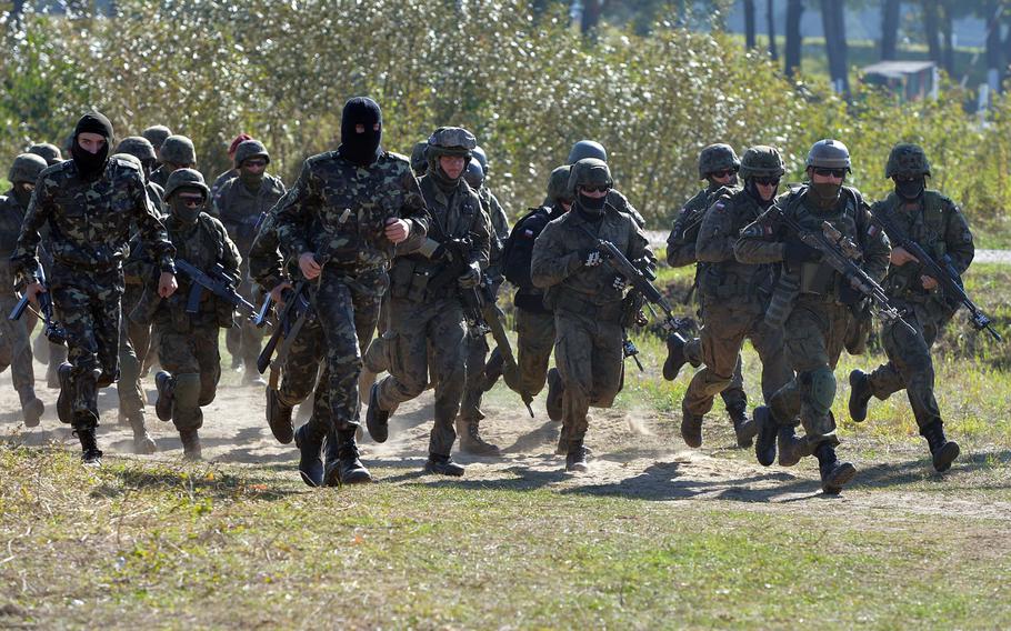Soldiers from various nations hustle back to the starting point after taking part in cordon-and-search training at Exercise Rapid Trident near Yavoriv, Ukraine, Friday, Sept. 19, 2014.